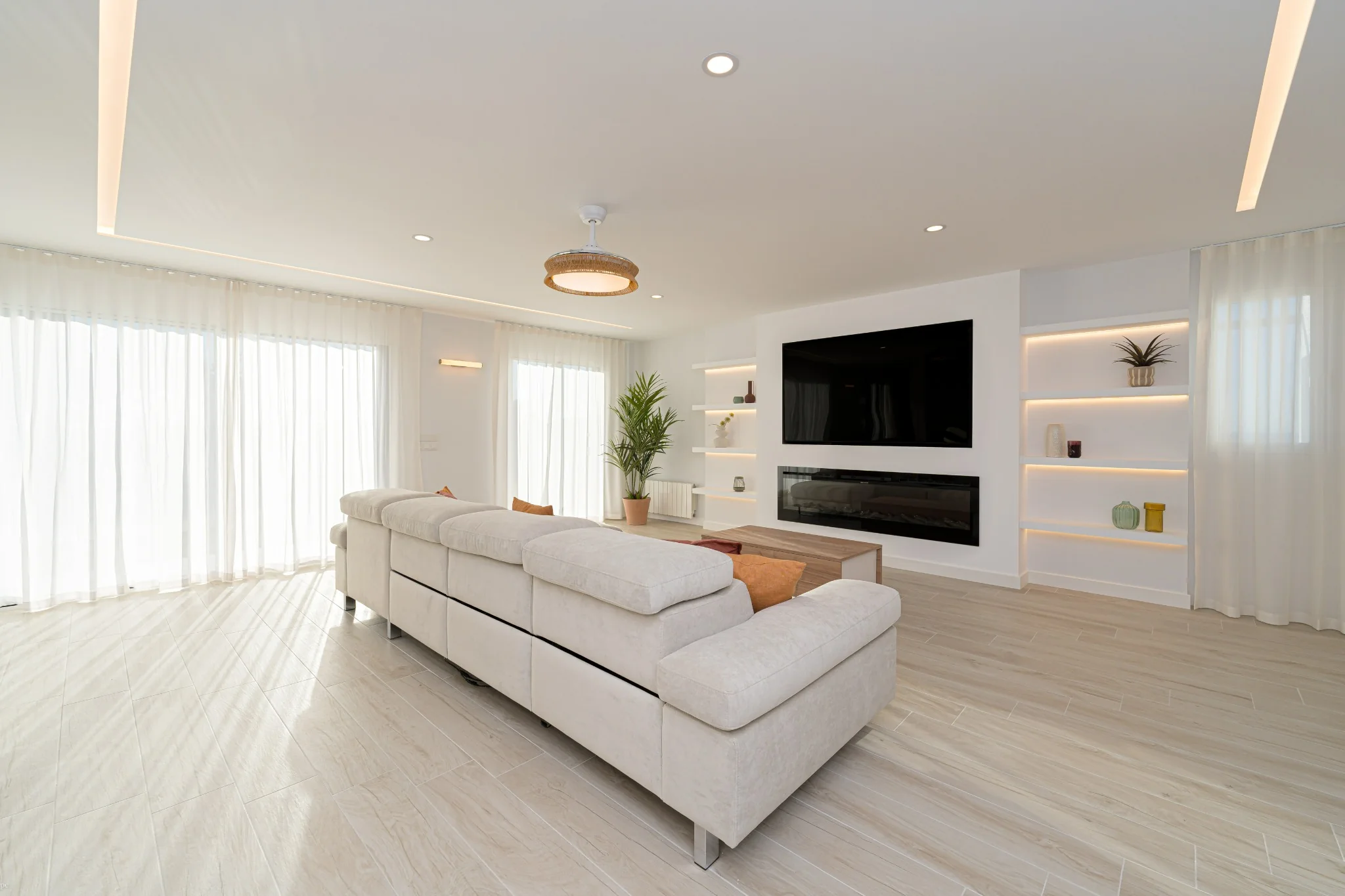 Salón de Costa Verde con mueble de televisión, chimenea e iluminación integrada