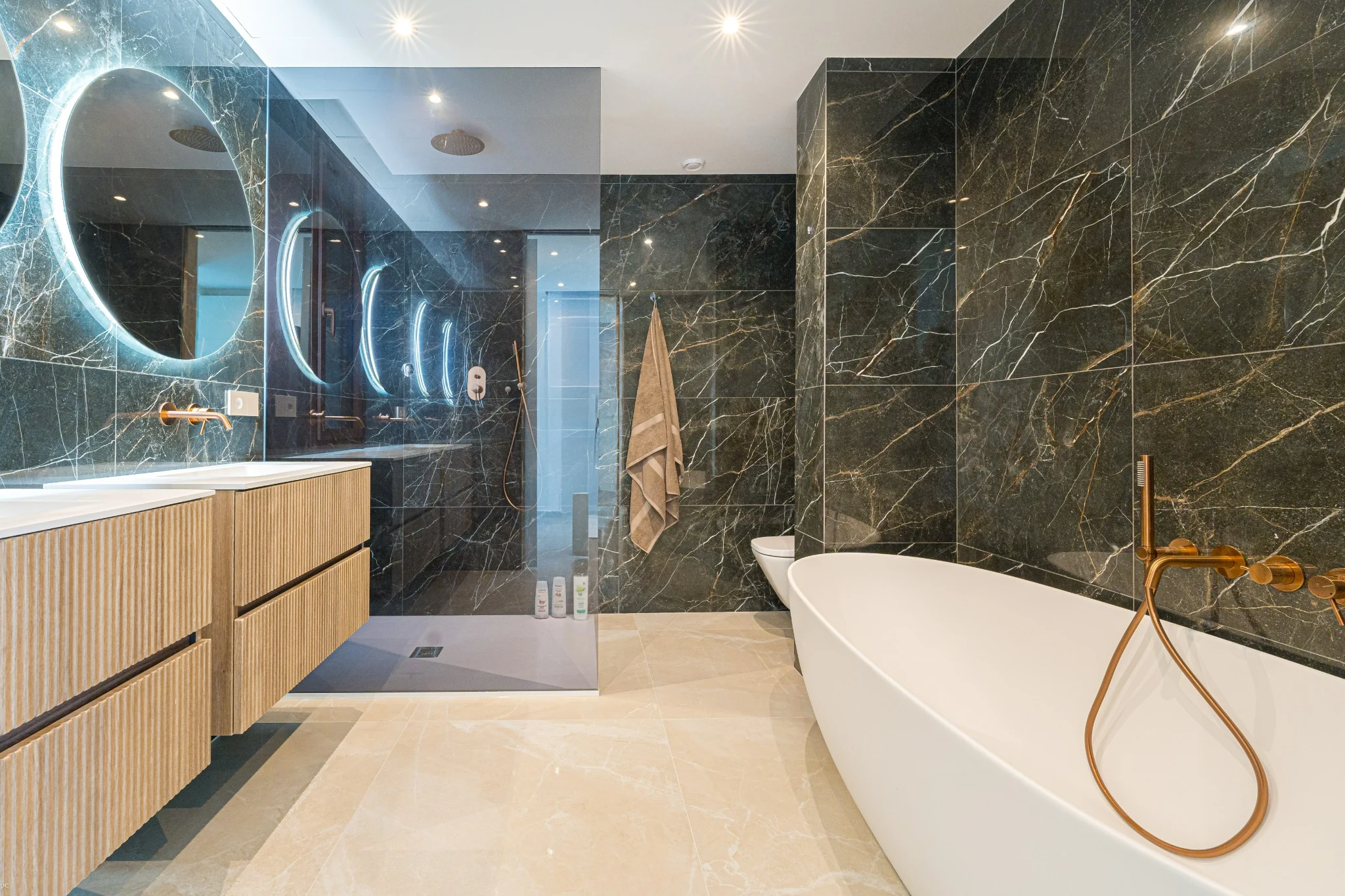 Baño principal de Mar de Bali con piedra oscura, madera y bañera